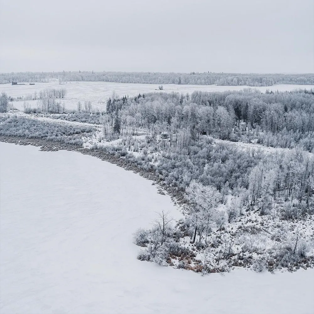 wide angle shot of ignis dome during winter with frozen lake and forest covered in snow