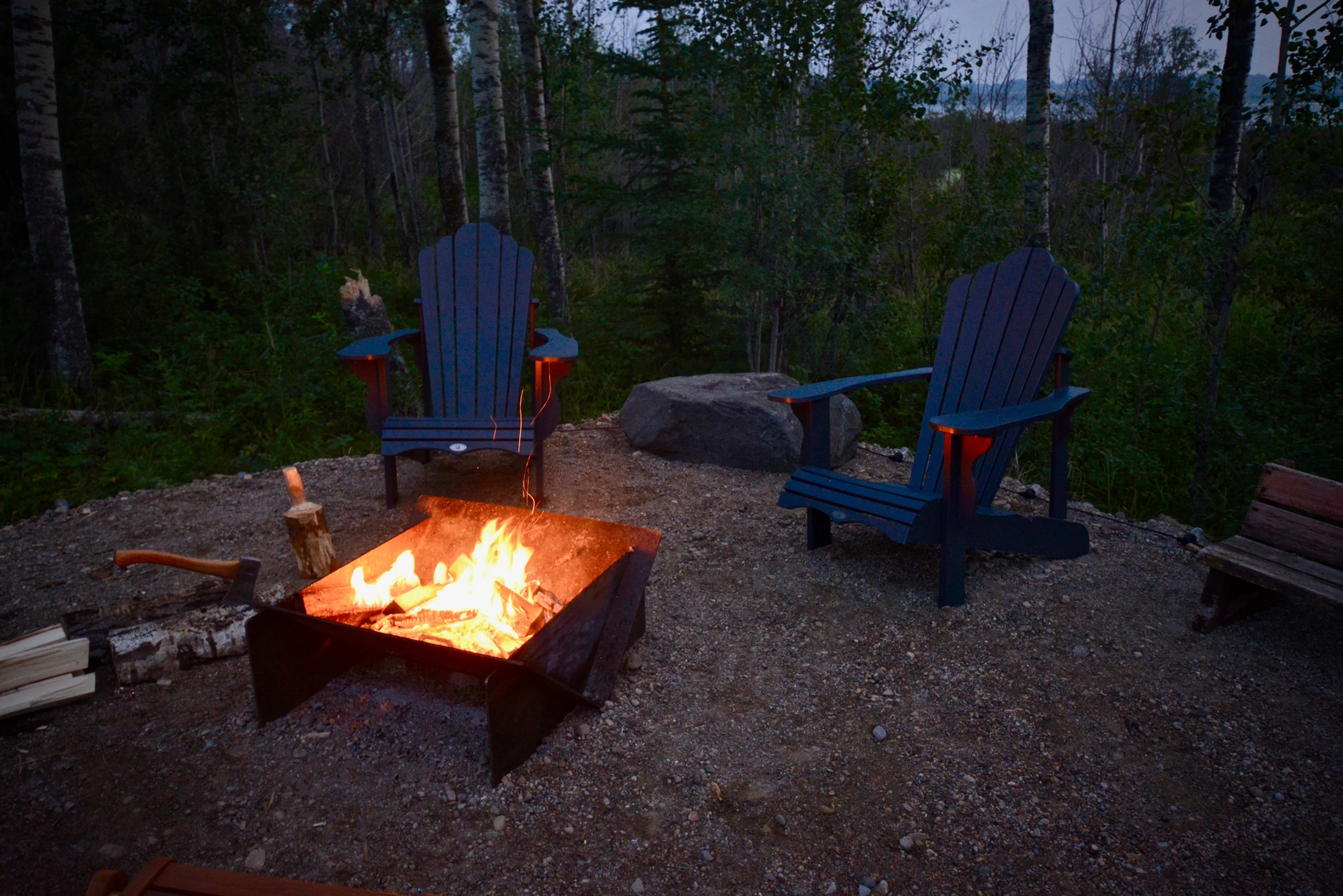 Large fire pit outside of ignis dome with two patio chairs with large roaring firing during the evening.
