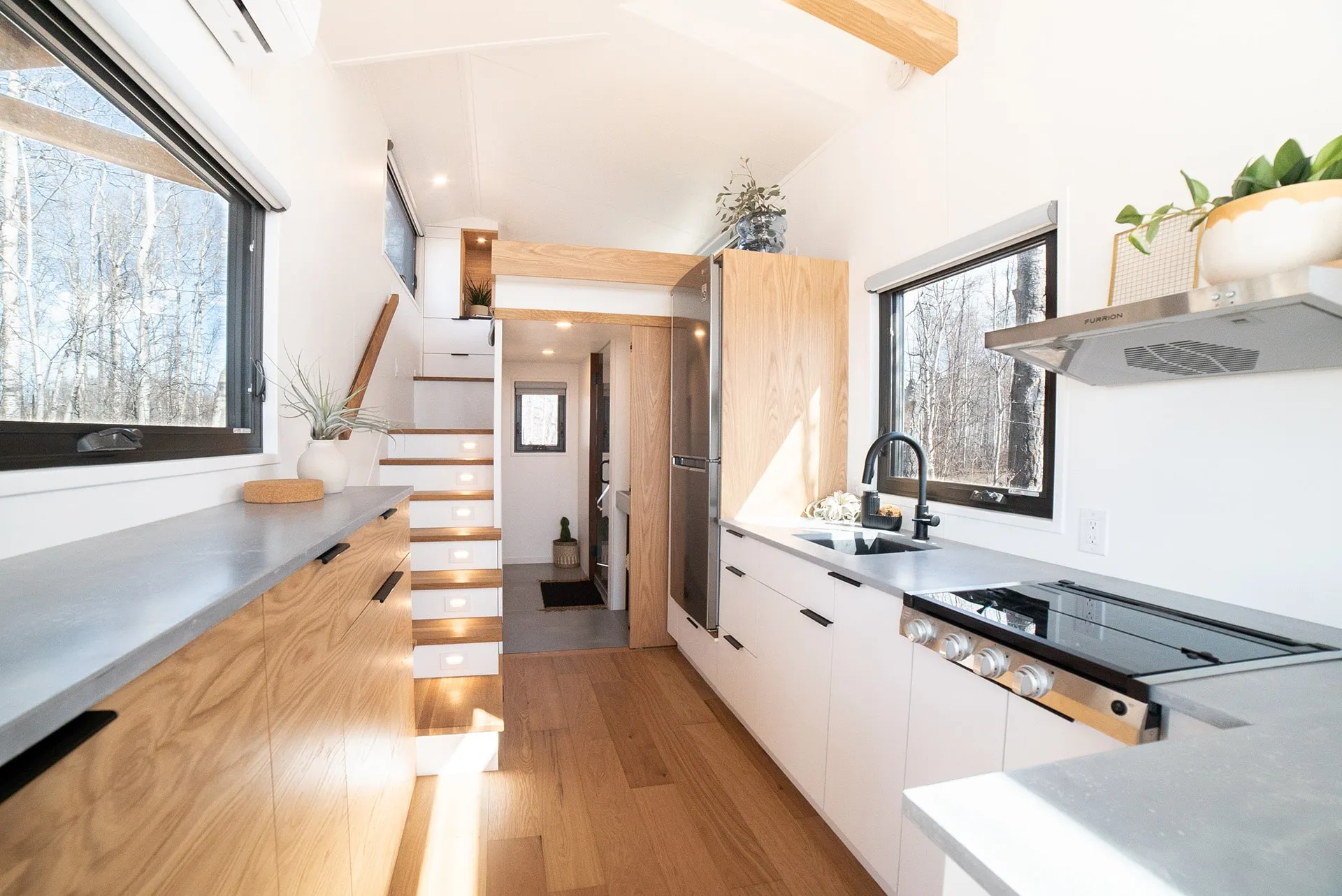 aqua tiny homes interior angled view of main floor with wider view of modern kitchen in a small space