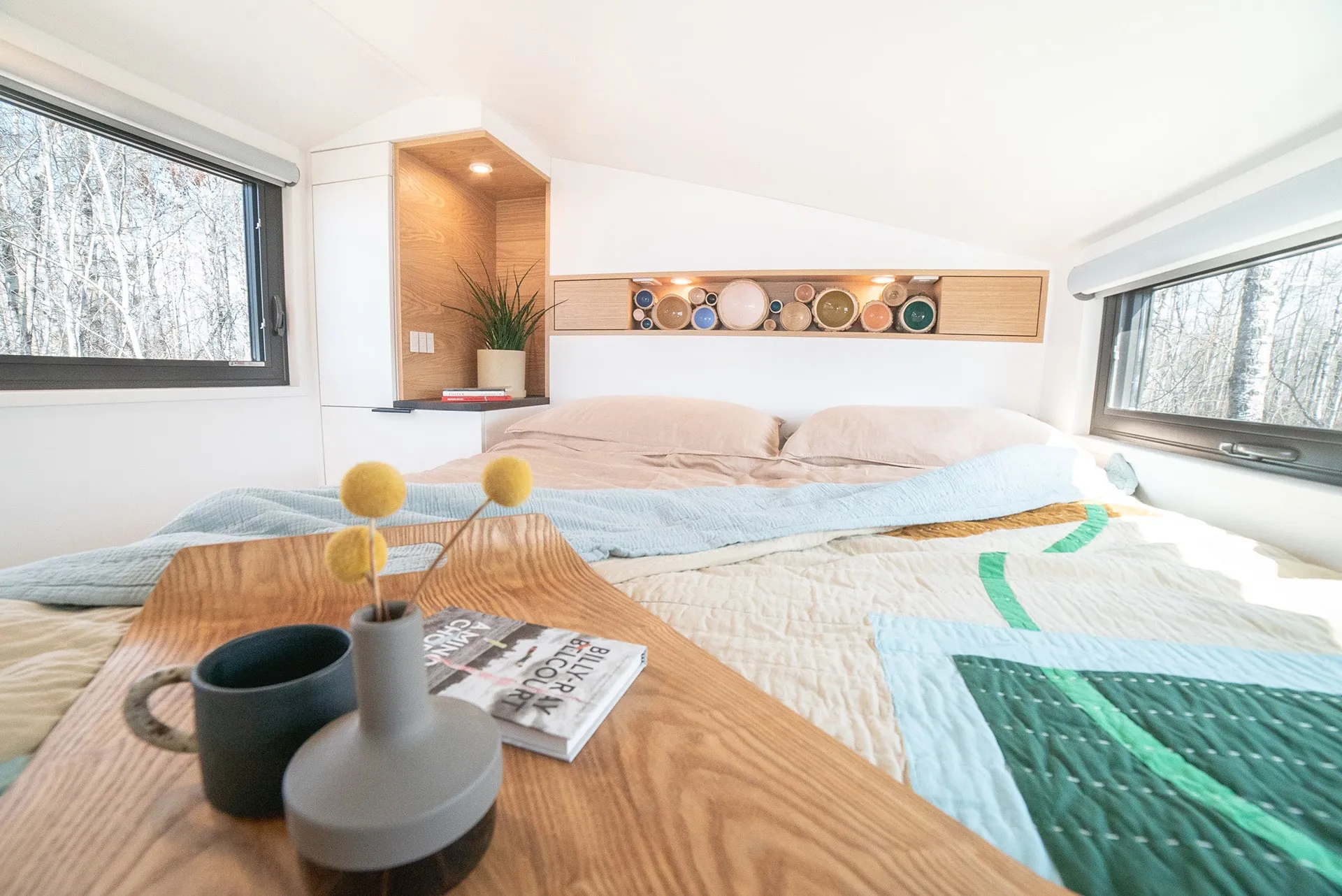 bed side view of aqua tiny homes small and cozy interior bedroom with queen size bed and custom shelf