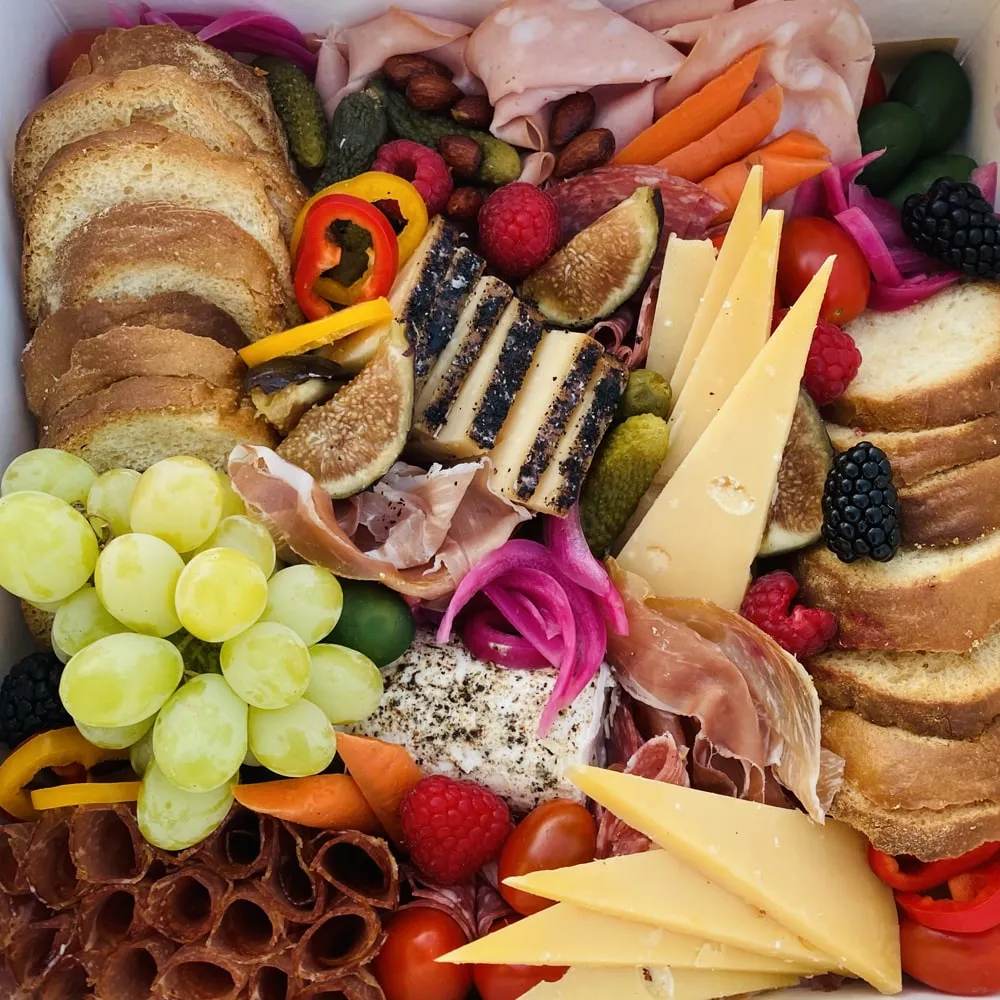 charcuterie board featuring grapes, cheese, cured meats and bread